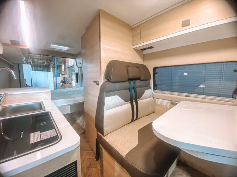foto del interior de una autocaravana en la que se observa el baño, los asientos y la cocina