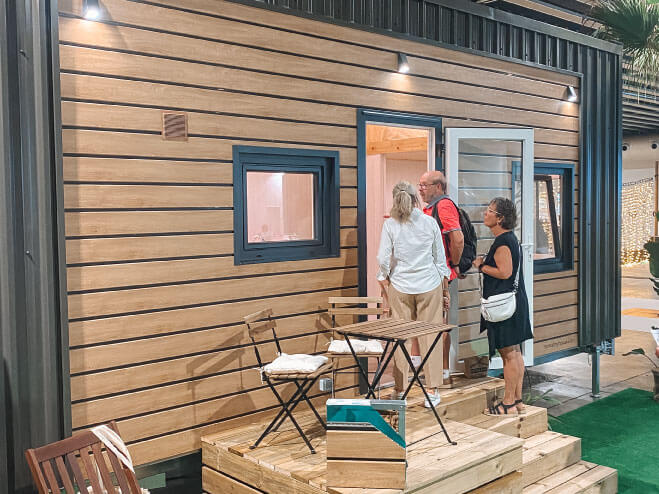 tres personas entrando en una casa construida con módulos prefabricados